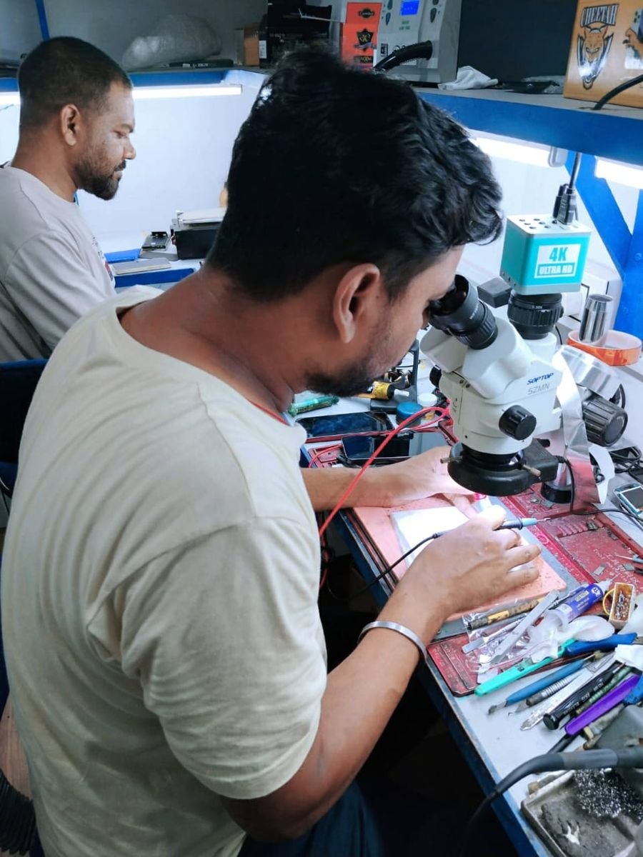 A MOBNET student repairing a circuit board under a microscope